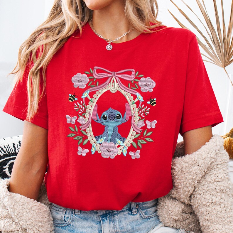 a woman wearing a red t - shirt with a picture of stitched stitching