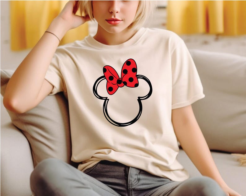 a woman sitting on a couch wearing a minnie mouse t - shirt
