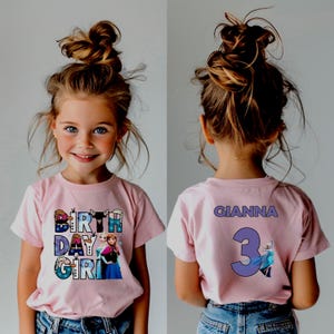 May include: A pink t-shirt with the words "BIRTH DAY GIRL" in a colorful design, featuring cartoon characters. The back of the shirt has the name "GIANNA" and the number "3".