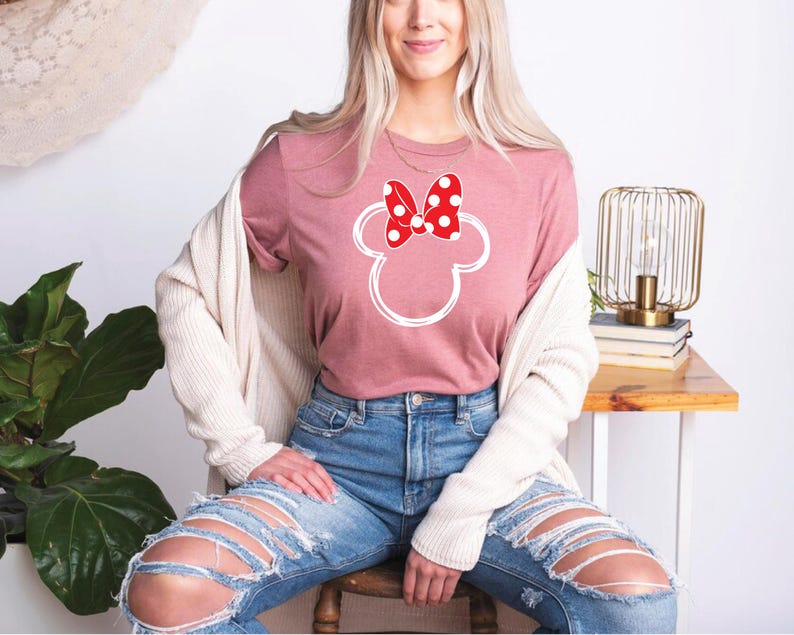 a woman sitting on a chair wearing a minnie mouse shirt