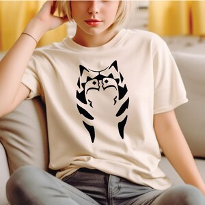 a woman sitting on a couch wearing a cat t - shirt