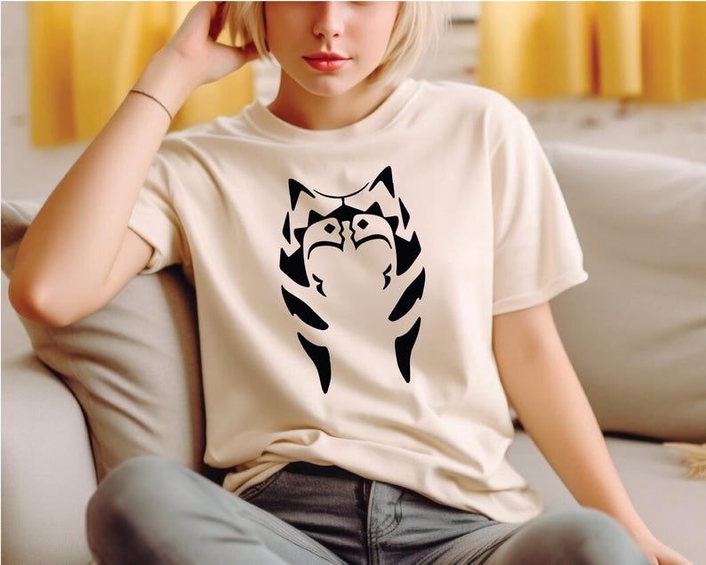 a woman sitting on a couch wearing a cat t - shirt