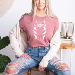 a woman sitting on top of a chair wearing ripped jeans