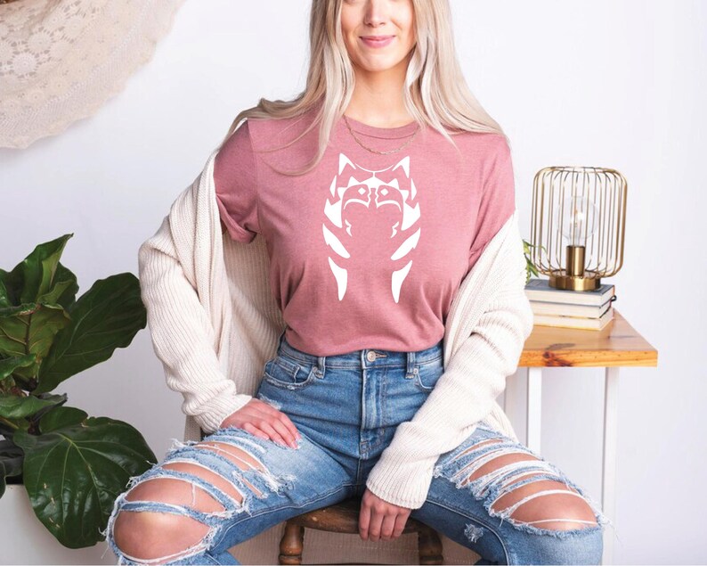 a woman sitting on top of a chair wearing ripped jeans