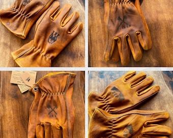 May include: A pair of brown leather work gloves with a distressed look. The gloves have a stitched cuff and a logo with crossed axes and the word "Timber" on the back of the hand.