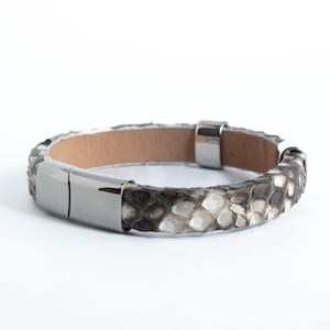 May include: A brown and white snakeskin leather bracelet with a silver clasp.