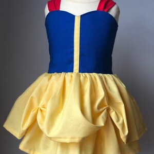 May include: A yellow and blue dress with red straps. The dress has a puffed skirt and a sweetheart neckline.