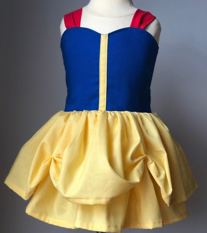 May include: A yellow and blue dress with red straps. The dress has a puffed skirt and a sweetheart neckline.