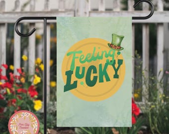 Może przedstawiać: Zielona, żółta i biała flaga ogrodowa z napisem "Feeling Lucky" w kółku z zielonym kapeluszem leprechauna na górze.