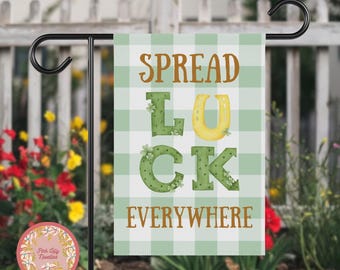 Może przedstawiać: Zielono-biała kratkowana flaga ogrodowa z napisem "SPREAD LUCK EVERYWHERE" w brązowych literach. Litery są ozdobione koniczyną i złotą podkową.