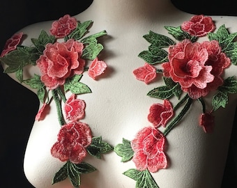 Puede incluir: Dos apliques florales con flores rosas y hojas verdes. Los apliques están en un busto de maniquí blanco.