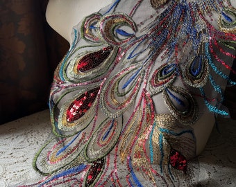 Puede incluir: Aplique bordada con diseño de pluma de pavo real con lentejuelas en tonos dorados, azules, verdes y rojos sobre una tela de malla transparente.