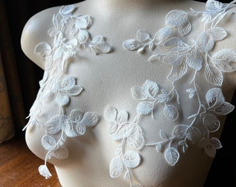 May include: White floral lace applique with delicate leaf and vine details. The applique is displayed on a mannequin, showcasing the intricate embroidery and design. Perfect for bridal wear or other craft projects.