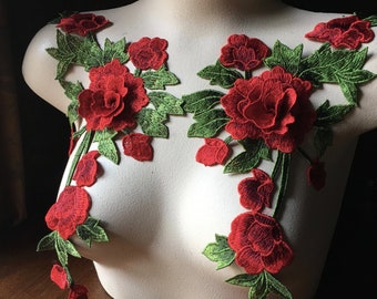 May include: Two red floral appliques with green leaves on a white mannequin bust. The appliques are made of fabric and have a 3D effect.