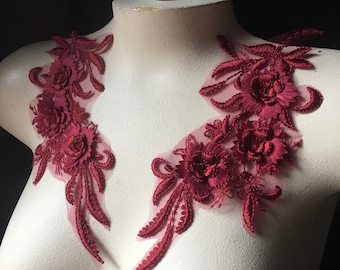 May include: Two burgundy floral lace appliques with delicate embroidery and a sheer mesh background. These appliques are perfect for adding a touch of elegance to any garment.