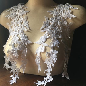 Op de afbeelding: Twee witte kant-applicaties met bloemenmotieven, perfect om kleding of knutselwerk een vleugje elegantie te geven.