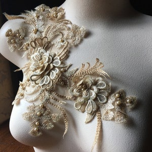 May include: Gold lace applique with pearl embellishments. The lace features floral designs and delicate details. This applique is perfect for adding a touch of elegance to any project.