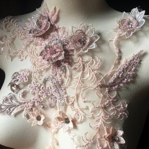 May include: A delicate floral applique with pink and beige embroidery and beads. The applique features a variety of flowers and leaves, and is perfect for adding a touch of elegance to any project.