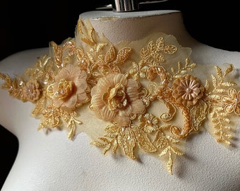 Op de afbeelding: Gouden kantversiering met delicate bloemenmotieven en parelaccenten. De versiering heeft een doorschijnende gaasrug en is perfect om een ​​toets van elegantie aan elk project toe te voegen.