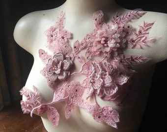 May include: Pink floral lace applique with pearl and rhinestone embellishments. This delicate lace design is perfect for adding a touch of elegance to any project.