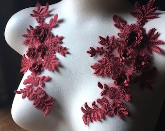 May include: Two burgundy lace appliques with floral designs. The appliques are made of delicate lace and feature intricate floral patterns. They are perfect for adding a touch of elegance to any project.