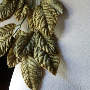 May include: A sprig of artificial leaves made of velvet fabric. The leaves are a deep green color and have a textured surface.