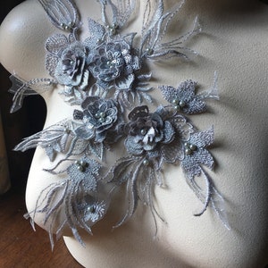 May include: Silver floral lace applique with pearl embellishments. The applique features delicate floral designs and intricate details.
