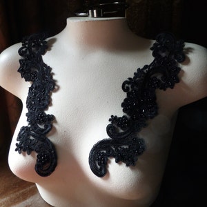 Puede incluir: Dos apliques de encaje negro con adornos de cuentas, perfectos para añadir un toque de elegancia a una prenda.