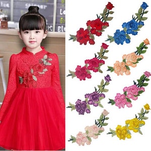 May include: Assortment of ten embroidered iron-on patches featuring a cluster of roses with stems and leaves. The patches are available in ten colors: red, blue, pink, purple, orange, yellow, light pink, dark pink, light blue, and dark blue.