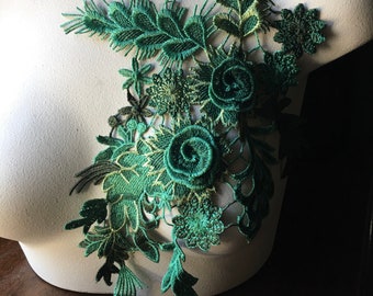 Puede incluir: Aplique de encaje floral verde con un diseño de hojas. El encaje es delicado e intrincado, con una variedad de formas y tamaños de flores.