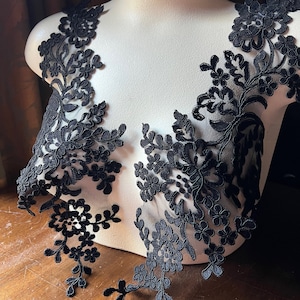 Puede incluir: Dos aplicaciones de encaje negro con dise&ntilde;os florales. Las aplicaciones est&aacute;n en un busto de maniqu&iacute; blanco.