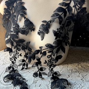 May include: Two black lace appliques with floral designs. The appliques are made of delicate lace and feature intricate floral patterns. They are perfect for adding a touch of elegance to any project.