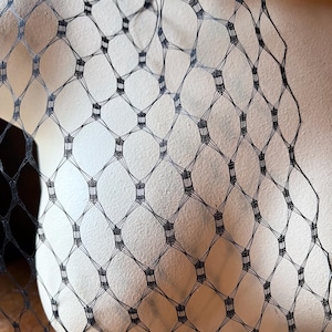 May include: Black netting fabric with a diamond pattern. The netting is delicate and has a soft, flowing texture.