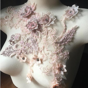 Op de afbeelding: Een delicate roze en witte bloemenkant applique met parel accenten. De applique heeft verschillende bloemvormen en -maten, met een delicaat, vrouwelijk ontwerp.