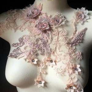 May include: A delicate lace applique with pink and brown floral designs and beaded accents. The applique is perfect for adding a touch of elegance to clothing, accessories, or home decor.