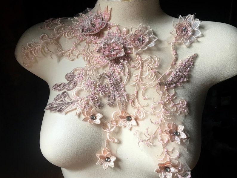 May include: A delicate lace applique with pink and brown floral designs and beaded accents. The applique is perfect for adding a touch of elegance to clothing, accessories, or home decor.