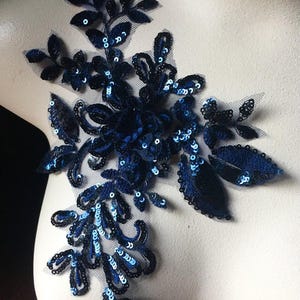 Puede incluir: Aplique floral azul con lentejuelas y hojas de terciopelo negro. Esta decoración es perfecta para añadir un toque de brillo a la ropa, los accesorios o los proyectos de decoración del hogar.