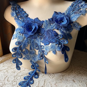 May include: Blue floral lace applique with a peacock feather design. The applique features two large blue flowers and a trailing design of peacock feathers.