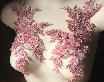 May include: Two pink floral lace appliques with beaded embellishments. The appliques are on a white mannequin bust.