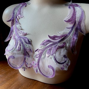 Könnte beinhalten: Lila und silberne florale Spitzenapplikation mit Pailletten. Diese zarte Spitzenborte ist perfekt, um jedem Projekt einen Hauch von Eleganz zu verleihen.