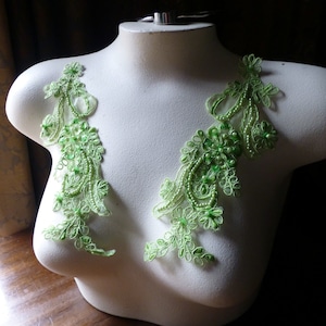Op de afbeelding: Twee groene kant-applicaties met parelversiering, perfect om een ​​bruidsjurk of ander kledingstuk voor speciale gelegenheden een vleugje elegantie te geven.
