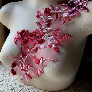 以下が含まれることがあります： 薄い生地にピンクと赤のフラワー刺繍のアップリケ。アップリケは、繊細な花と葉をヴィンテージスタイルで表現しています。