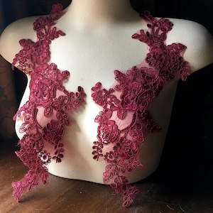 May include: Two burgundy lace appliques featuring floral designs. The appliques are made of delicate lace with a floral pattern and are ideal for adding a touch of elegance to any project.