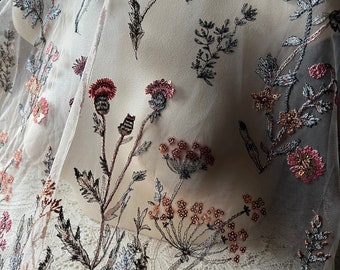 以下が含まれることがあります： ベージュのチュール生地に、ピンク、ブラウン、グレーの刺繍された花柄のデザインが施されています。花は、スパンコールとビーズでできています。