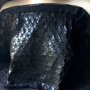 May include: A black strapless top with a geometric pattern of small black circles. The top is made of a stretchy fabric and has a fitted silhouette.