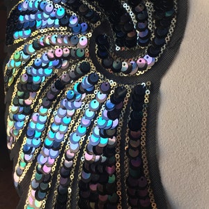 May include: A black fabric applique with iridescent blue and purple sequins arranged in a swirling pattern.