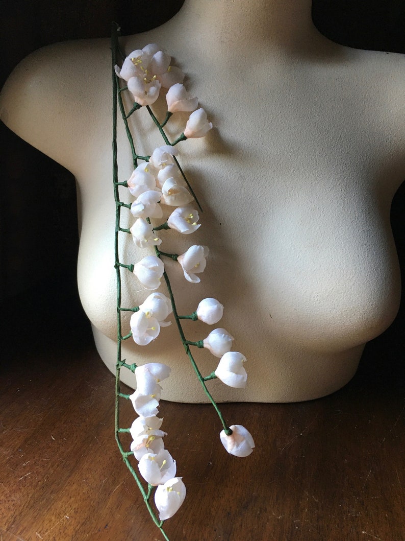 May include: A long strand of white artificial flowers with green stems. The flowers are arranged in clusters along the stems.