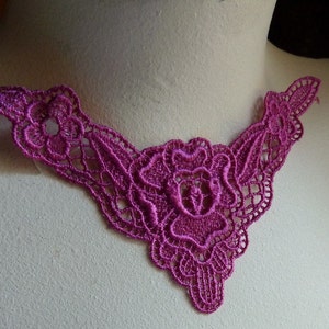 May include: A pink lace trim with a floral design. The lace is delicate and intricate, with a scalloped edge.