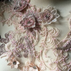 May include: Pink and beige floral lace applique with beaded details. The lace features delicate floral designs and intricate beading.