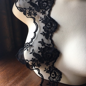 May include: Black lace trim with a floral design. The lace is delicate and has a scalloped edge.